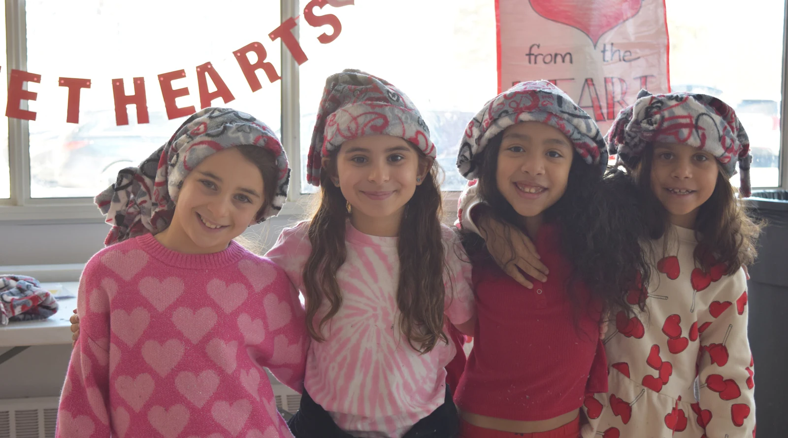 happy students pose together wearing handmade hats