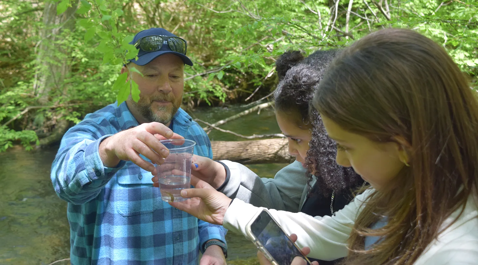 students examine a tiny trout before releasing it into a stream