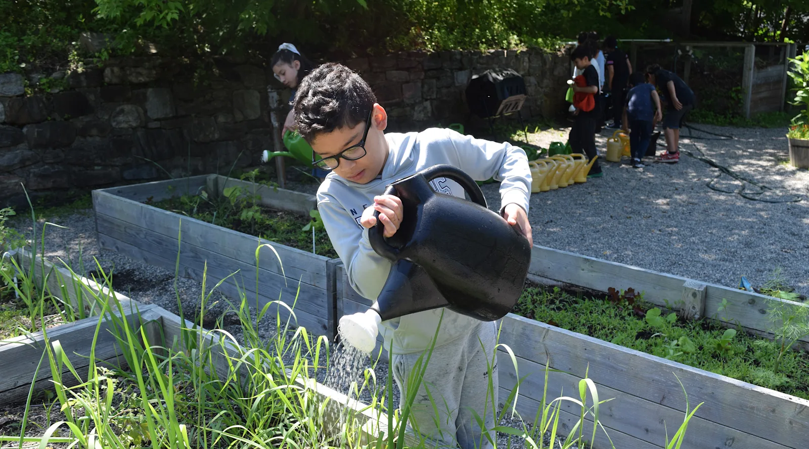 a student waters plants in the garden